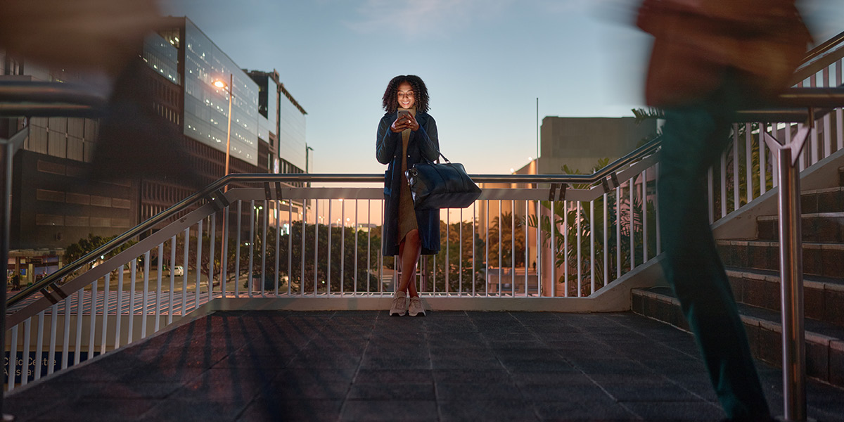 Woman on city stairs at dusk using smartphone